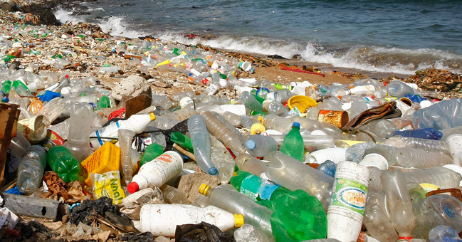 Plastikmüll am Strand, im Hintergrund das Meer