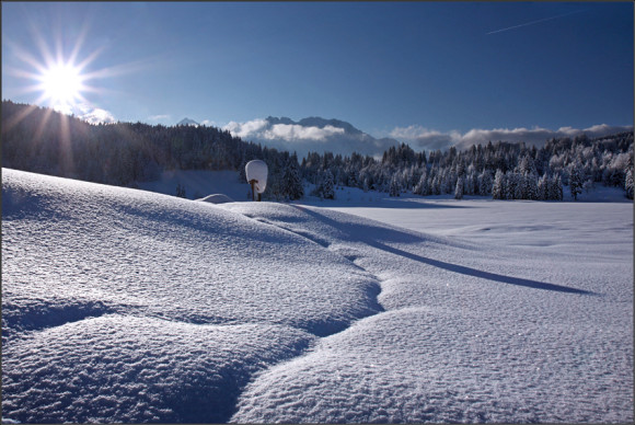 Sonne scheint über die Berggipfel auf frisch gefallenen Schnee.