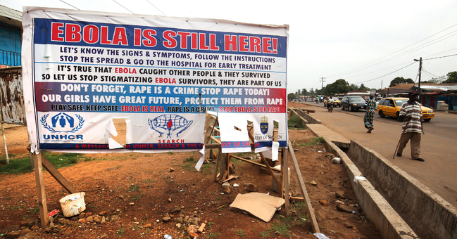 Liberians pass a sign warning about Ebola in Paynesville City in Liberia.